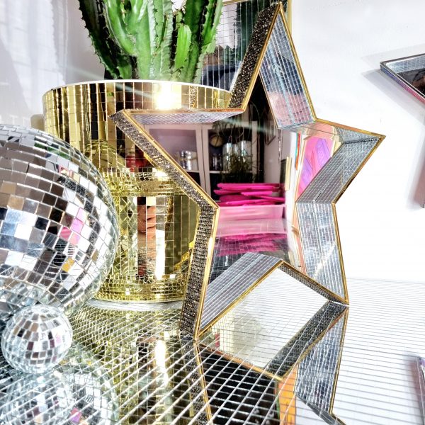 A mirror in the shape of a star, with disco and studded rhinestone edging.