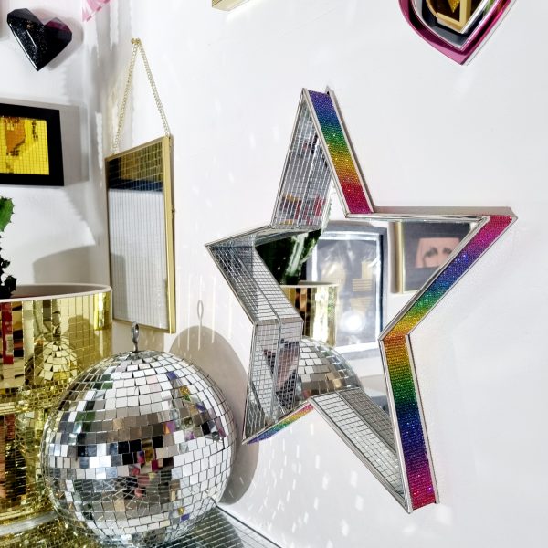 A MIRROR IN THE SHAPE OF A STAR, EDGED WITH DISCO MIRROR TILES AND RAINBOW RHINESTONES.