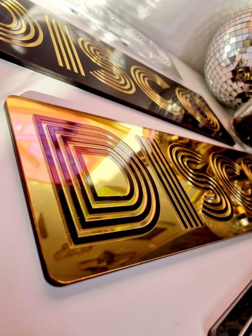 GOLD MIRRORED SIGN INLAID WITH BLACK DISCO LETTERING.