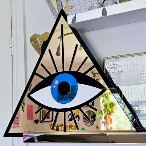 A mirror in the shape of an all seeing eye. The mirror is a gold triangle with an eye in the middle.