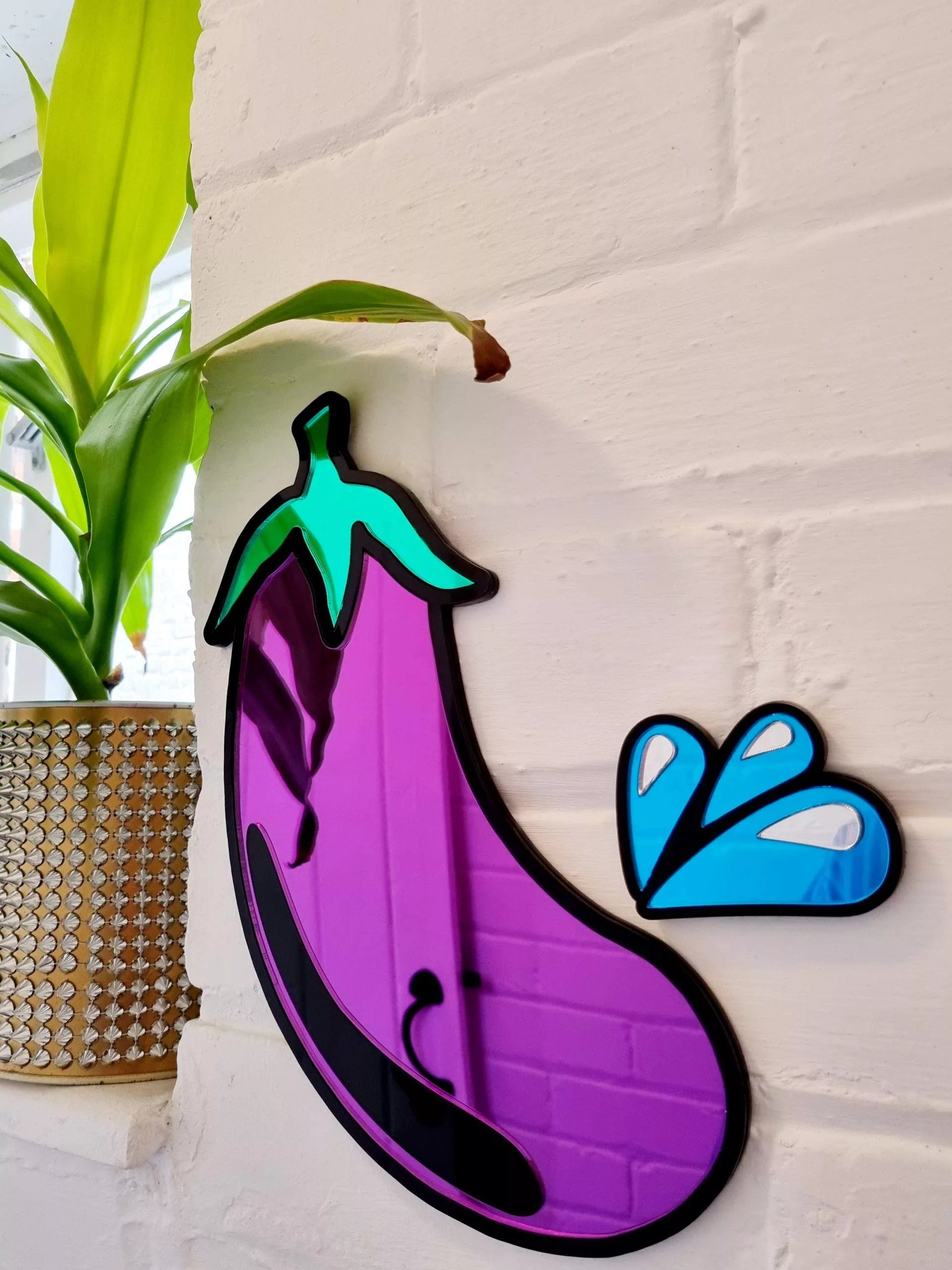 PURPLE AND BLACK MIRROR IN THE SHAPE OF AN AUBERGINE EMOJI.
