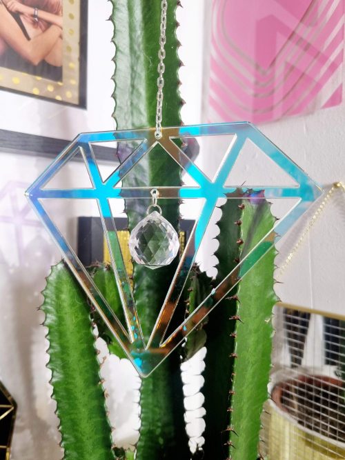 A suncatcher in the shape of a diamond, made with iridescent acrylic and finished with a faceted glass crystal.