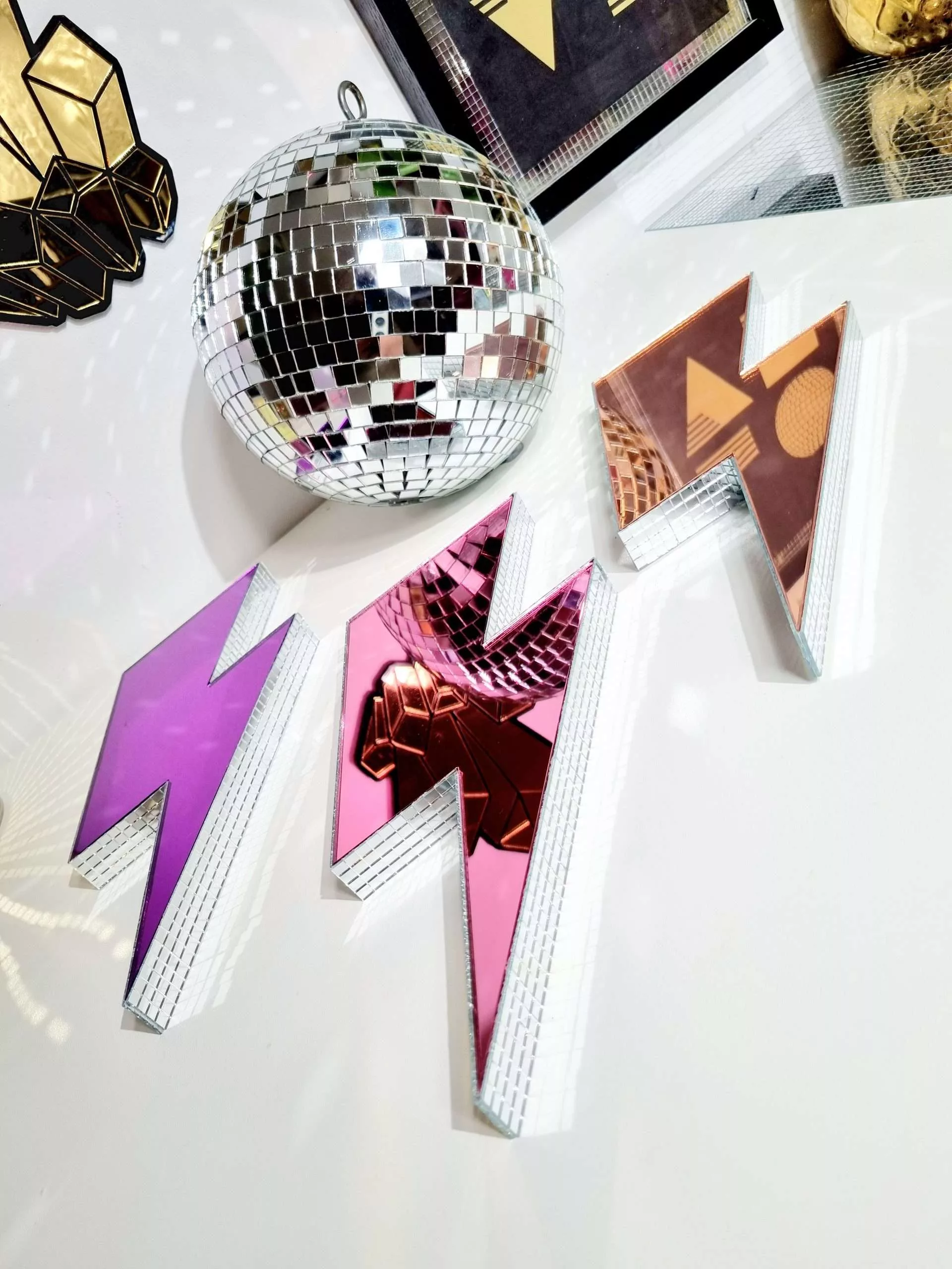 Handmade mirror lightning bolts in pink, purple and rose gold on a white background.
