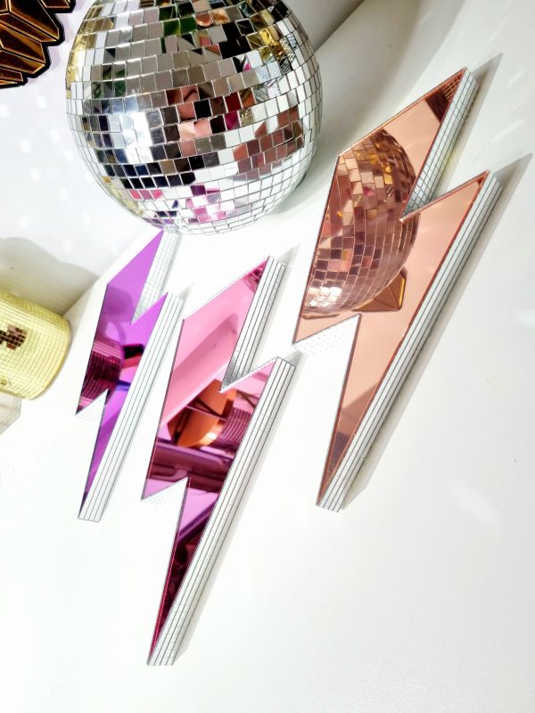 Handmade mirror lightning bolts in pink, purple and rose gold on a white background.