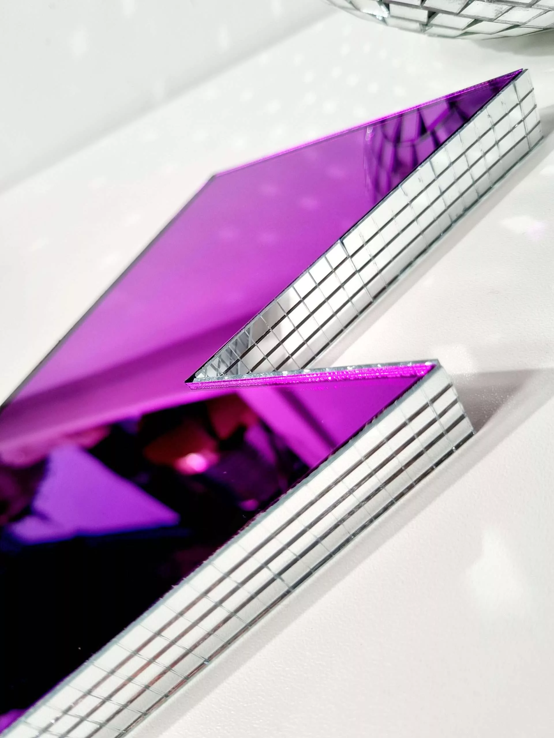 Handmade purple mirror lightning bolt on a white background.
