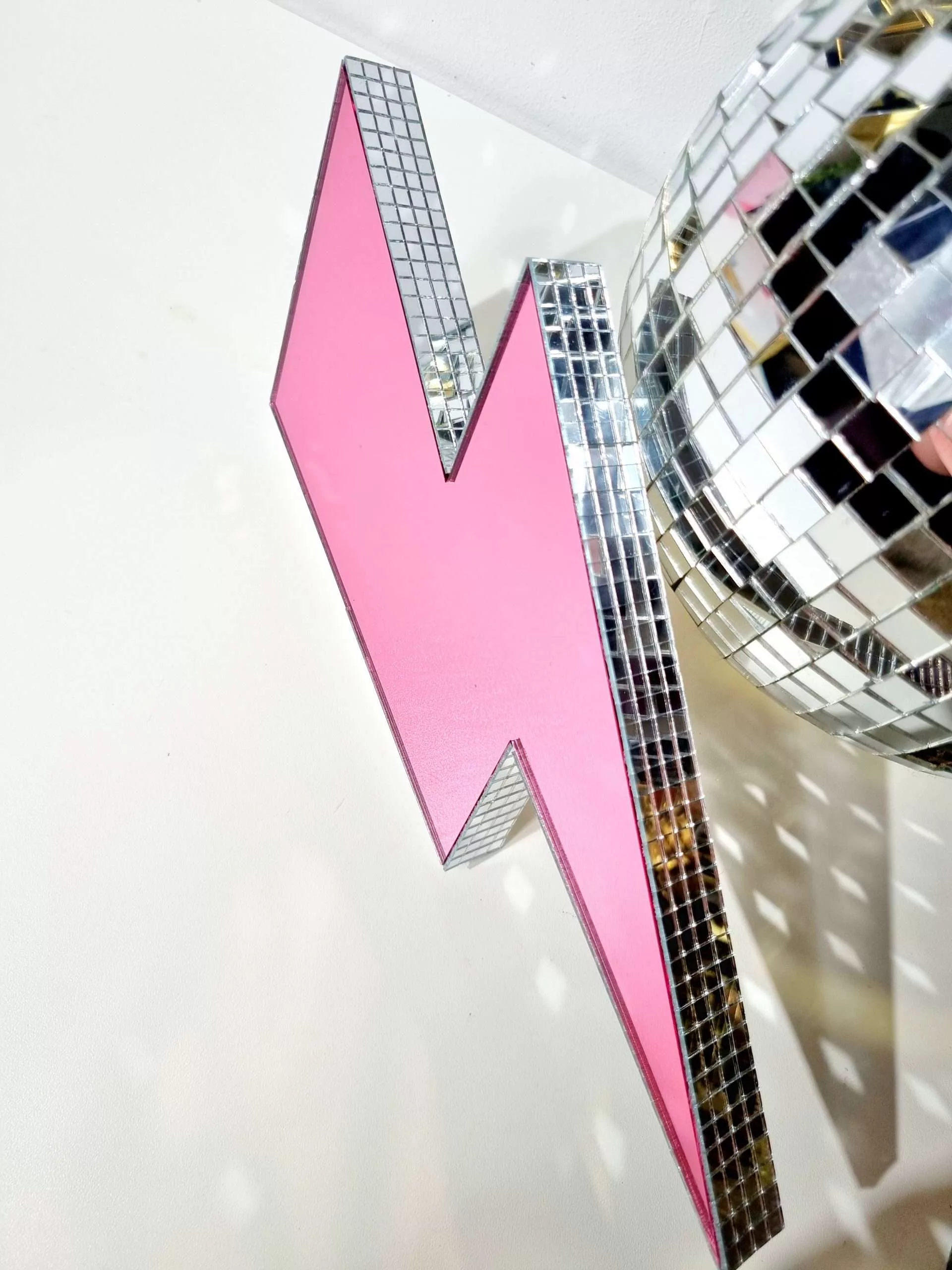 Handmade pink mirror lightning bolt on a white background.