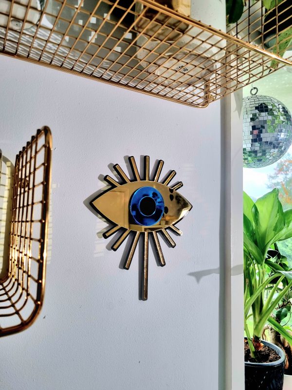 A handmade mirror in an Evil Eye design. Made with black, gold and blue acrylic.