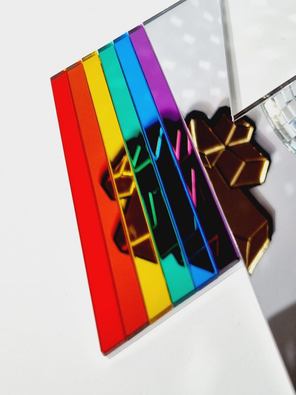 A handmade mirror in the shape of a lightning bolt. Most of the bolt is silver, with strips representing each colour of the rainbow.