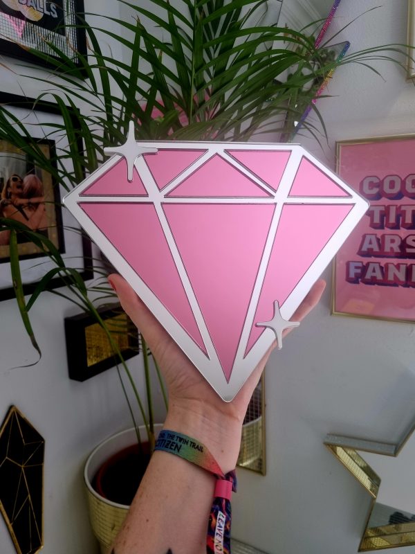 A mirrror in the shape of a diamond. Made with a silver mirror frame, and pink mirrored diamond pieces.
