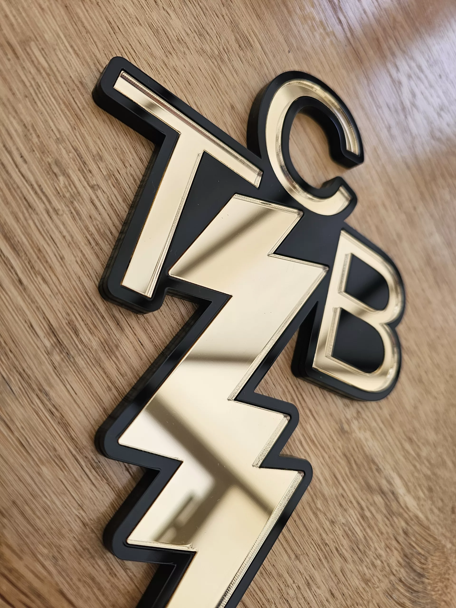 A piece of wall art made in the shape of the TCB necklace worn by Elvis Presley. Made with a black outline and mirror.