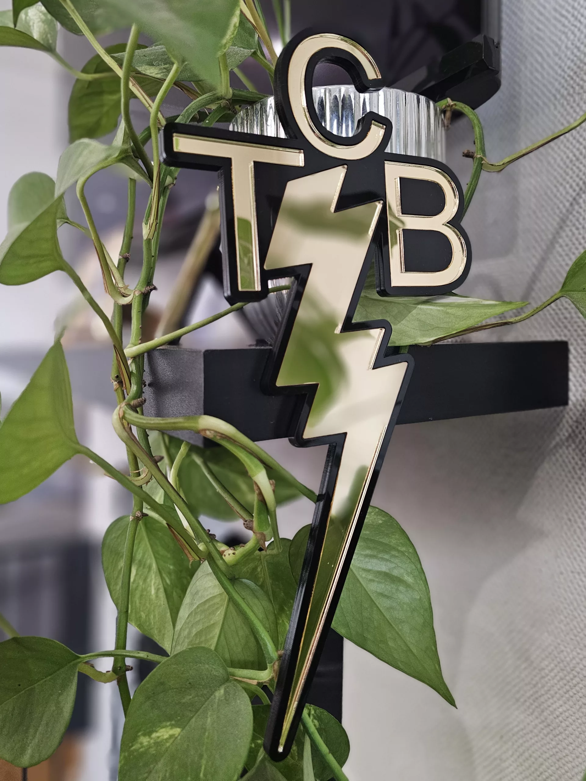 A piece of wall art made in the shape of the TCB necklace worn by Elvis Presley. Made with a black outline and mirror.