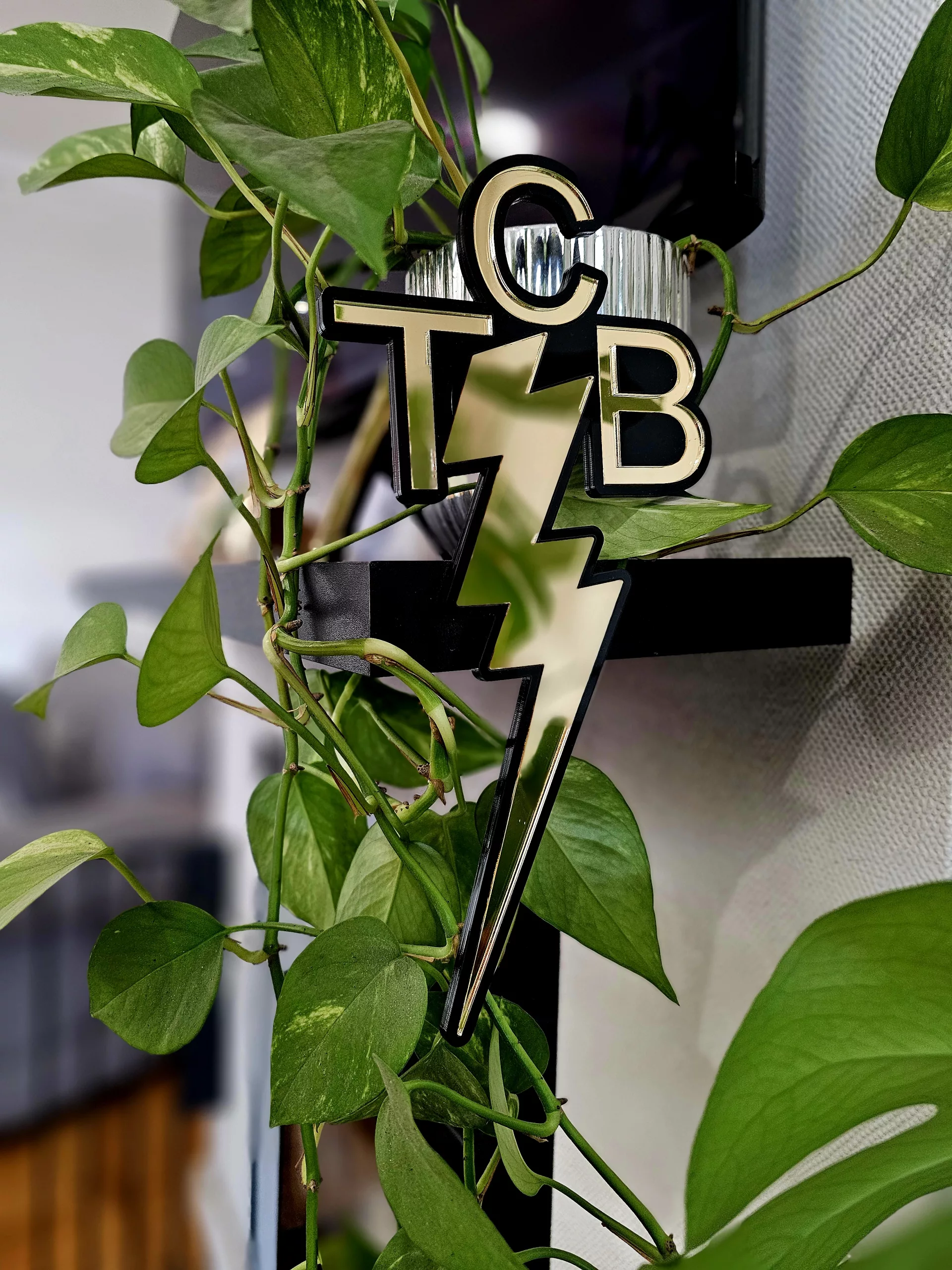 A piece of wall art made in the shape of the TCB necklace worn by Elvis Presley. Made with a black outline and mirror.