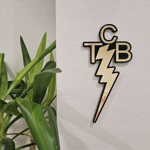 A piece of wall art made in the shape of the TCB necklace worn by Elvis Presley. Made with a black outline and mirror.