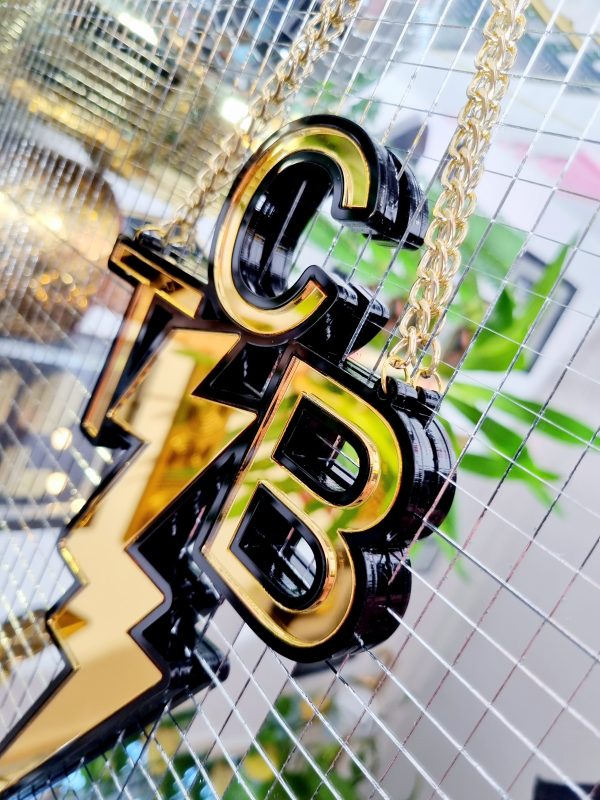 A handmade wall or door hanging in the style ofthe TCB necklace worn by Elvis Presley. The piece is gold with a black outline.