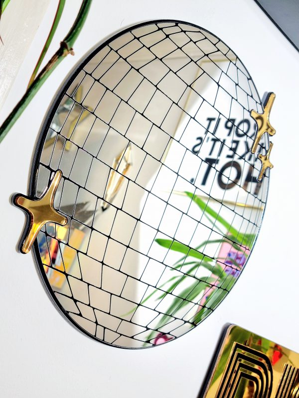 Handmade mirror in the shape and style of a disco ball. The round silver mirror is reverse engraved to show the details of the glitter ball. Finished with a black gloss backing and gold mirror twinkles.