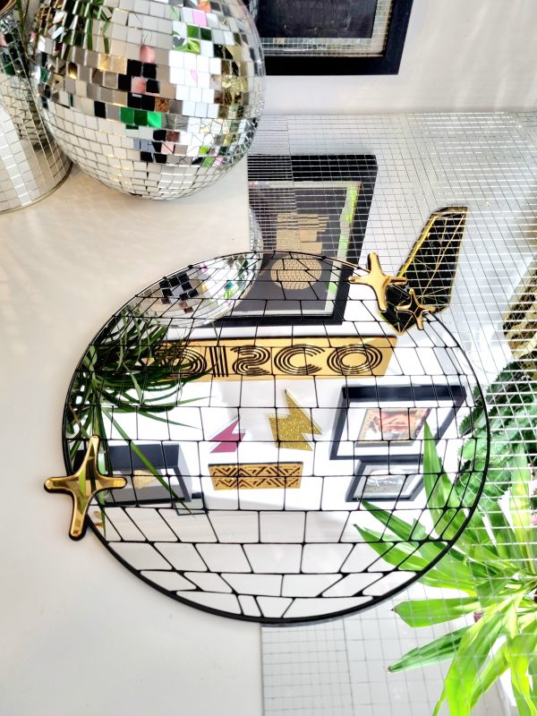 Handmade mirror in the shape and style of a disco ball. The round silver mirror is reverse engraved to show the details of the glitter ball. Finished with a black gloss backing and gold mirror twinkles.