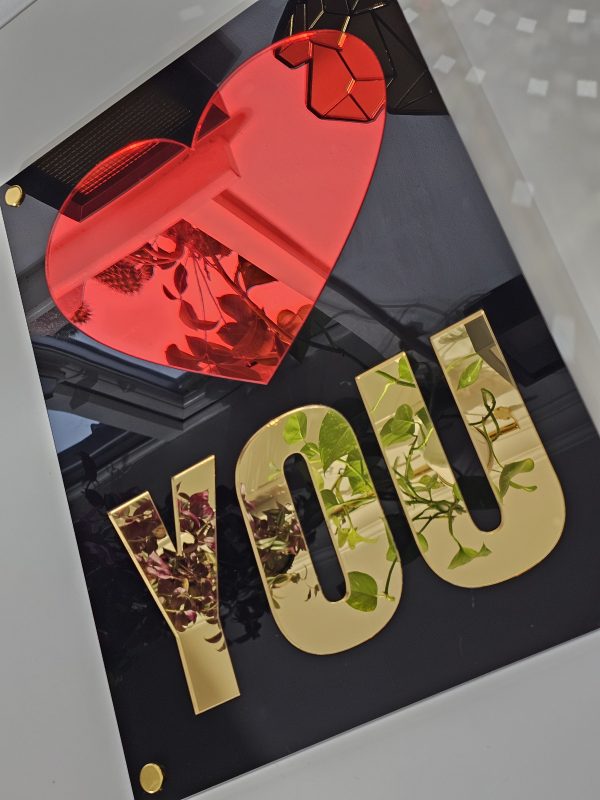 Wall art with a glossy black frame, red heart mirror and the word 'you' in gold mirror.