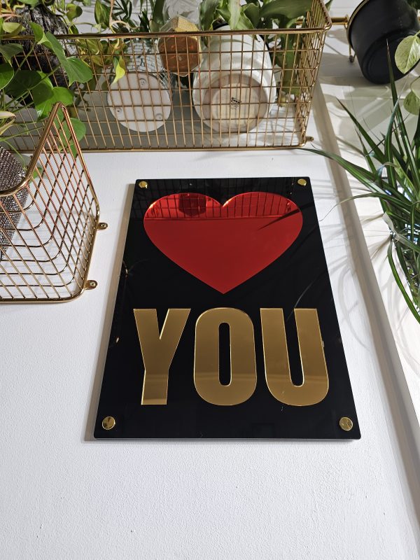 Wall art with a glossy black frame, red heart mirror and the word 'you' in gold mirror.