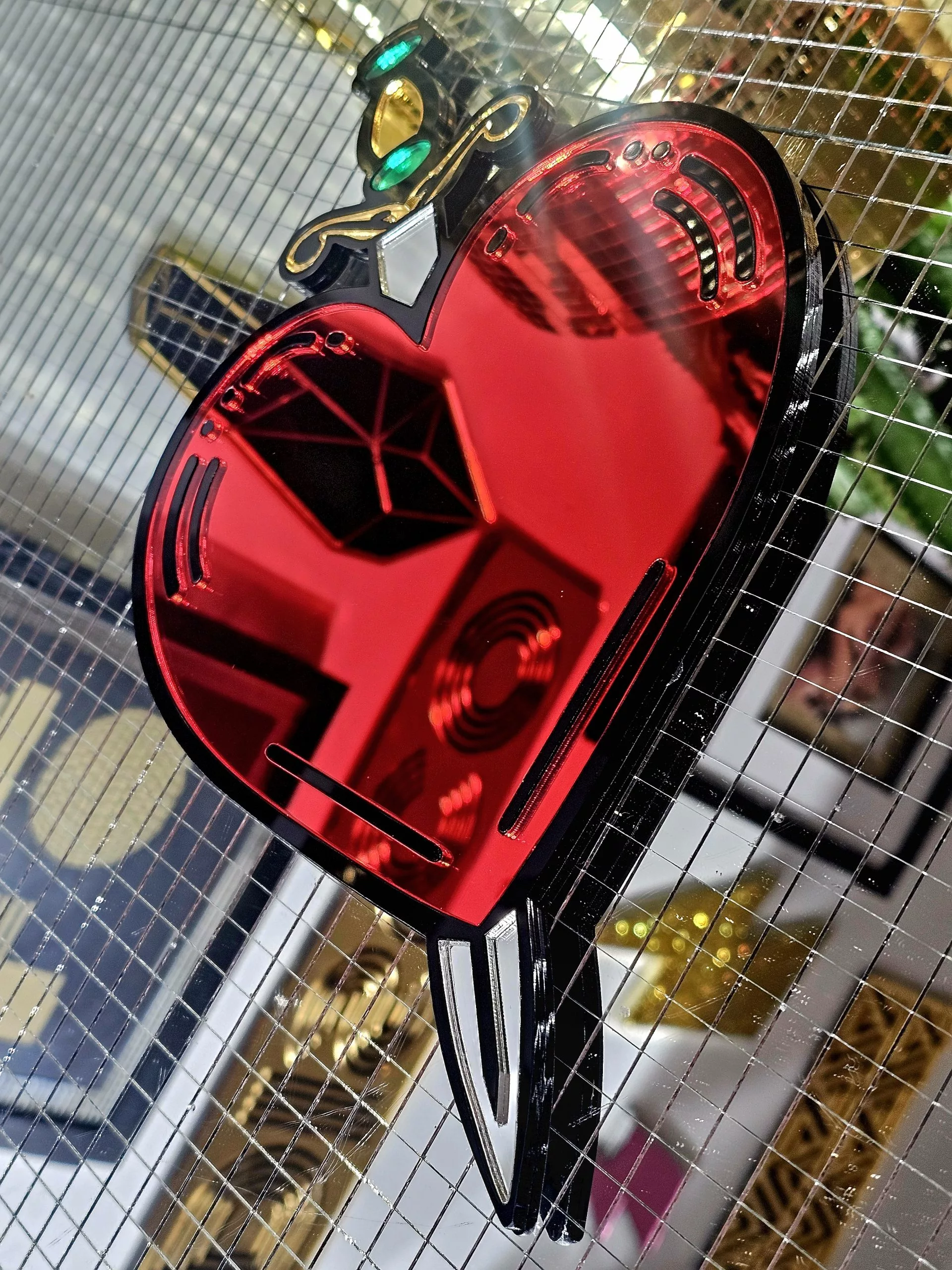 A handmade mirror in the shape of a heart and dagger, in an old school tattoo style. The heart is red with a black outline and orgate dagger design.