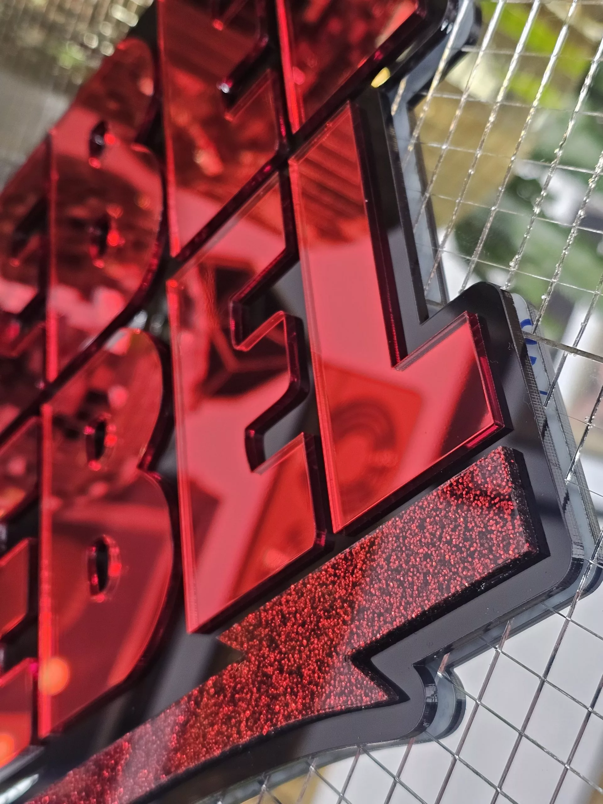 A piece of wall art with the text Rebel Rebel in red mirror with a black background.