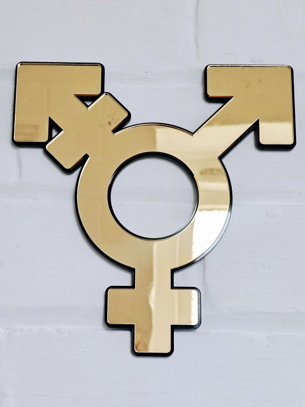 The transgender symbol made from gold mirror with a black backing. Mounted on a white brick wall.