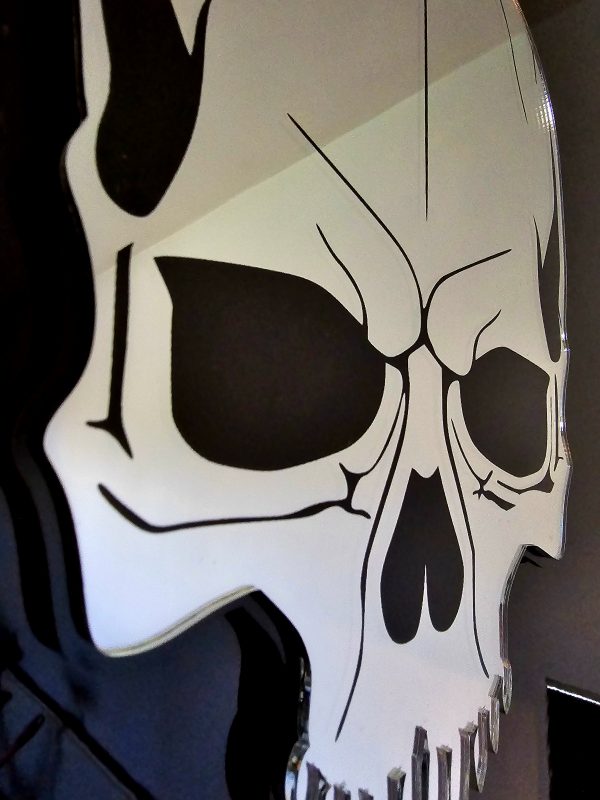 A mirror in the shape of s skull. The skull is made with silver mirror, with black details and a black outline.