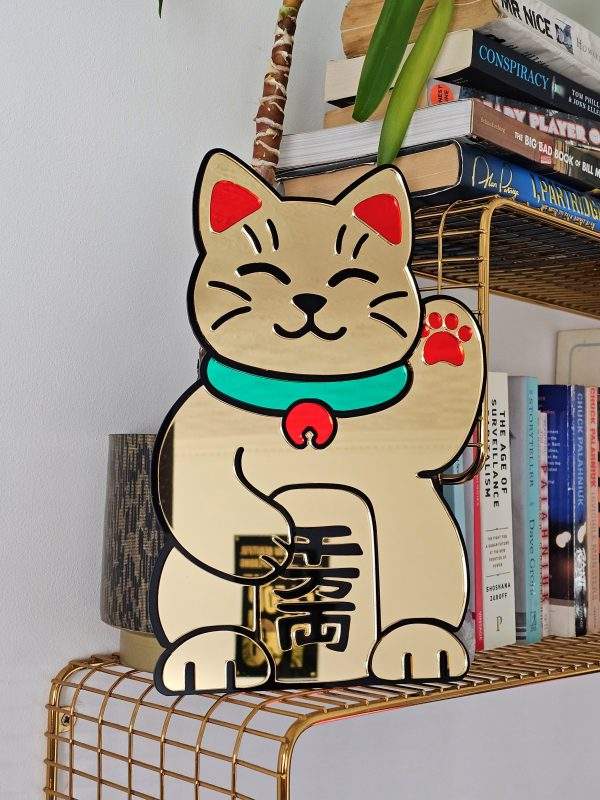 A handmade mirror in the shape of the Japanese waving cat. Made with gold mirror and black, gold and green accents.