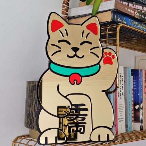 A handmade mirror in the shape of the Japanese waving cat. Made with gold mirror and black, gold and green accents.