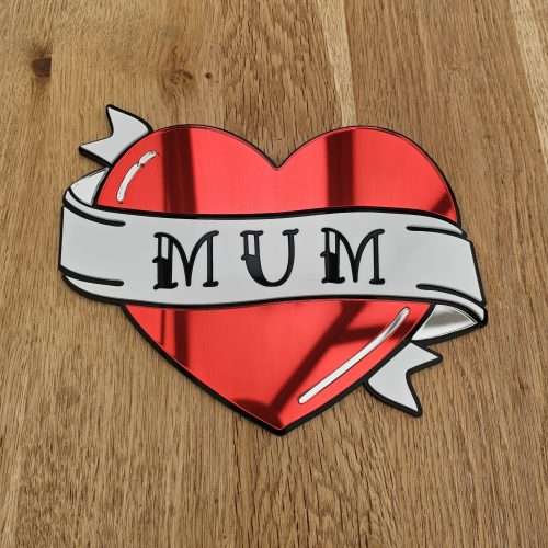 A handmade mirror in the shape of a heart with a banner running through the middle with the word mum. Made in an old school tattoo style.
