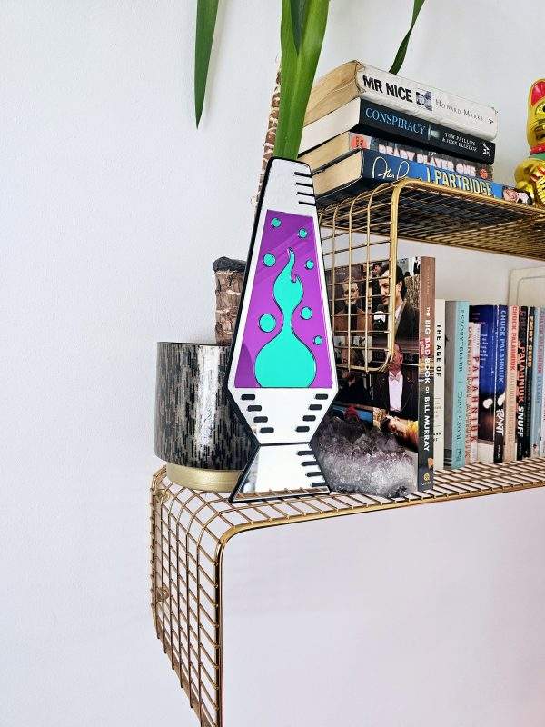 A mirror in the shape of a lava lamp. The lamp is silver, with purple and green 'liquid' pieces.