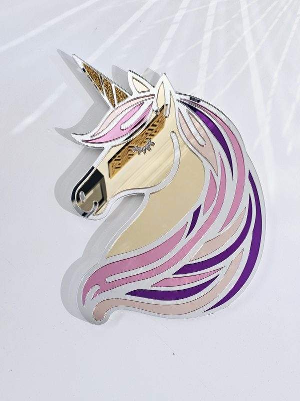 A mirror in the shape of a unicorn head. The unicorn has a silver mane with flecks of pink, purple and rose gold, with glitter horn and eyes.