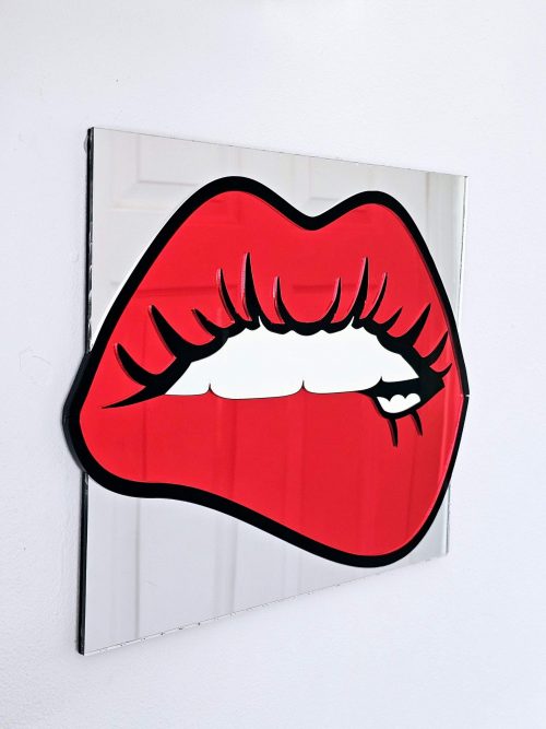 A handmade mirrorin the shape of lips. The lips are made in a pop art style with a black outline and red mirror lips.