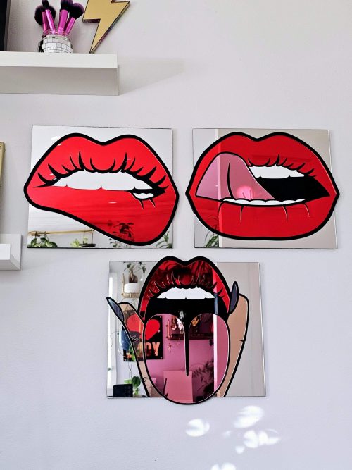 A mirror in the shape of lips. The lips are made in a pop art style with red mirror lips, a pink tongue and black outline.