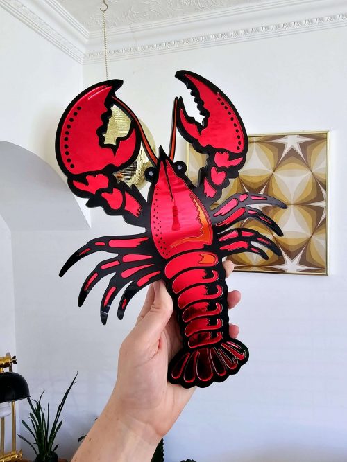 A handmade piece or mirror wall art in the shape of a lobster.