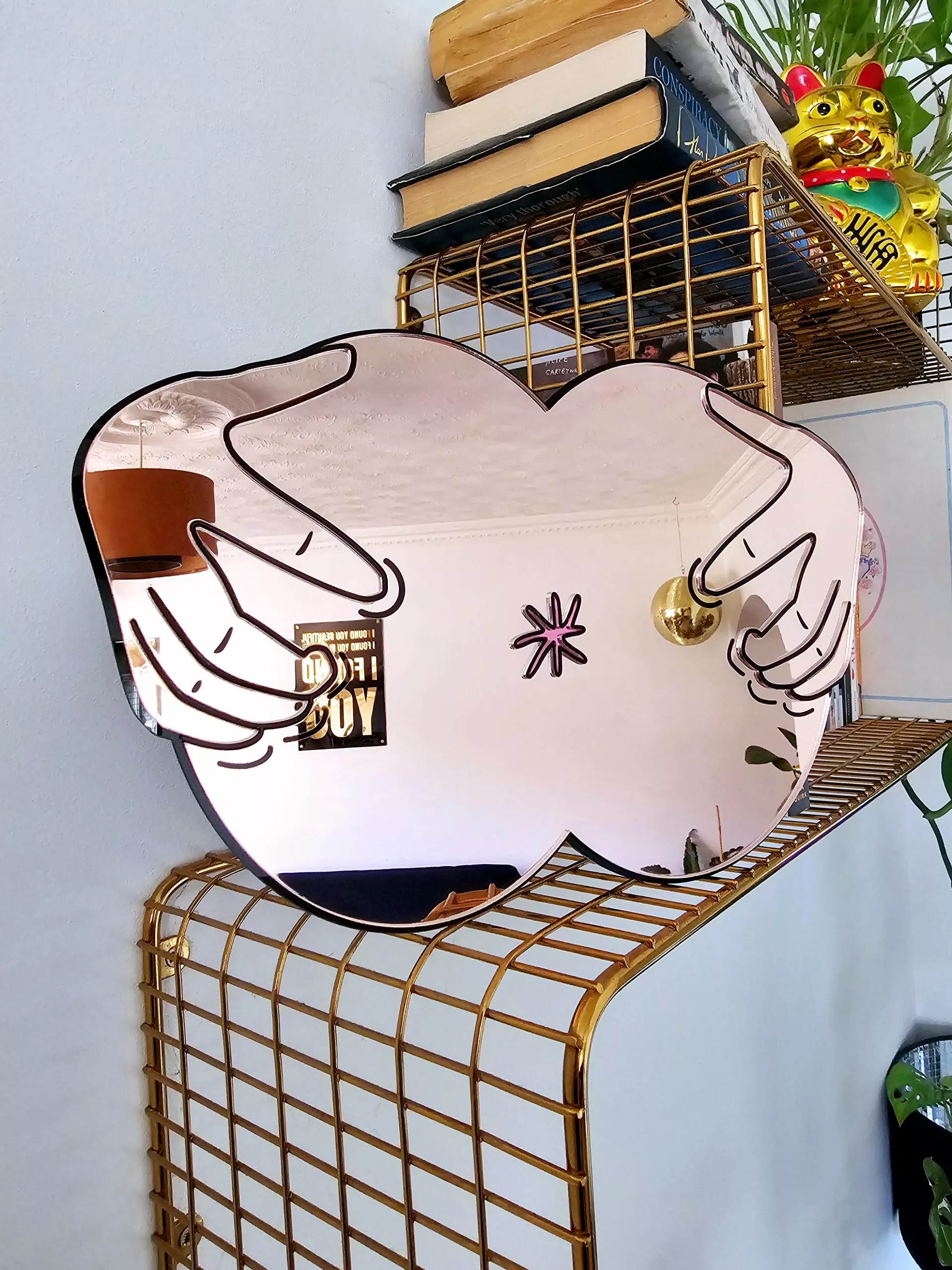 A handmade mirror in the shape of a butthole. The mirror hands pulling the butthole open.