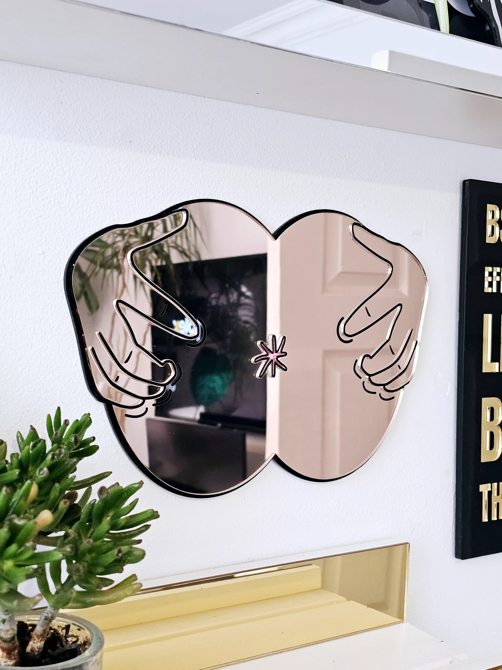 A handmade mirror in the shape of a butthole. The mirror hands pulling the butthole open.
