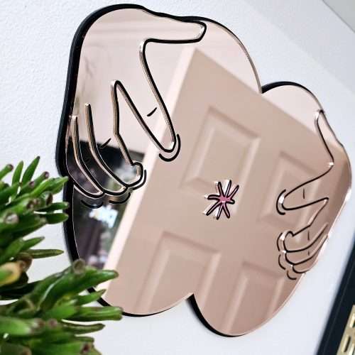 A handmade mirror in the shape of a butthole. The mirror hands pulling the butthole open.