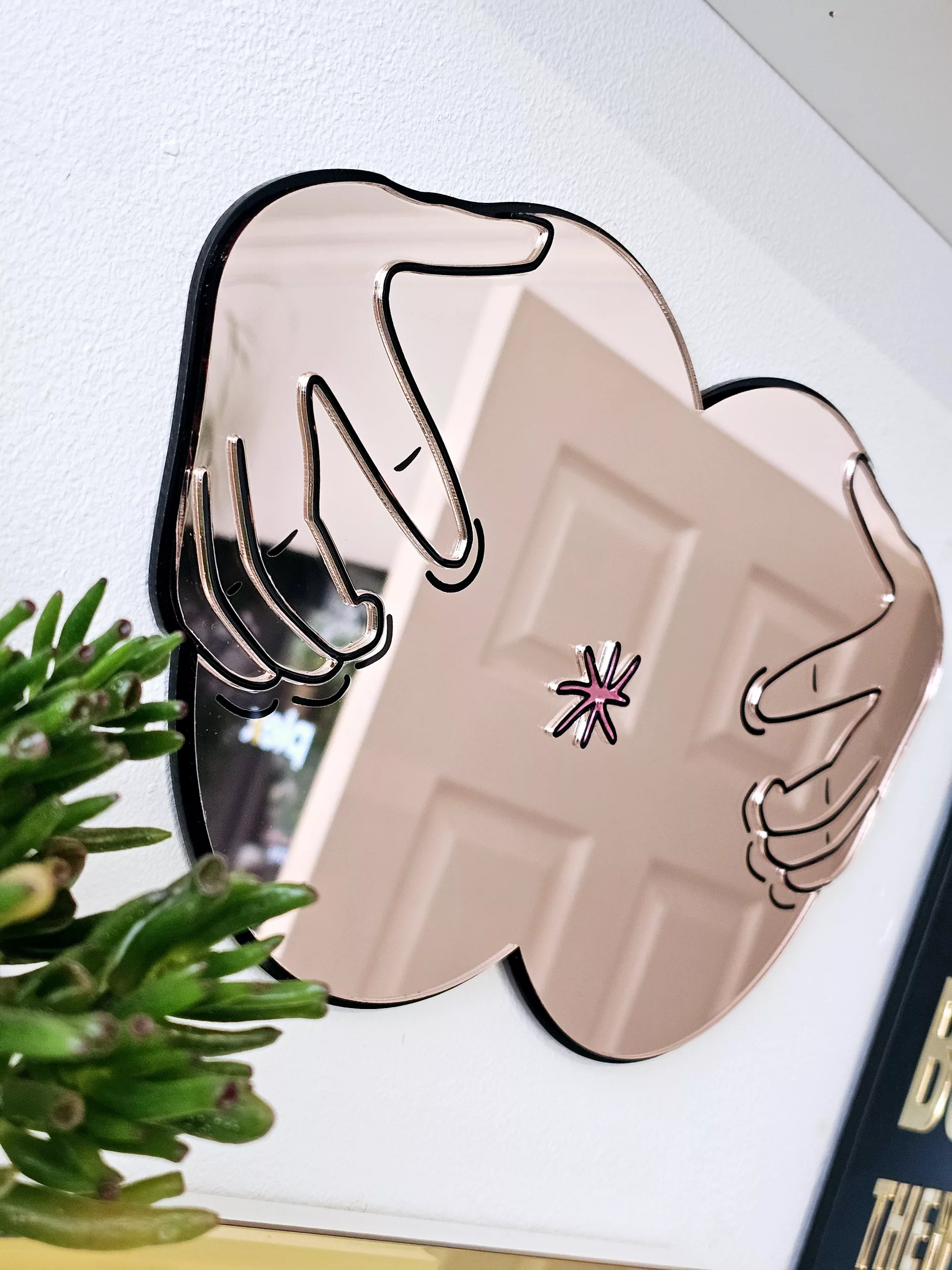 A handmade mirror in the shape of a butthole. The mirror hands pulling the butthole open.