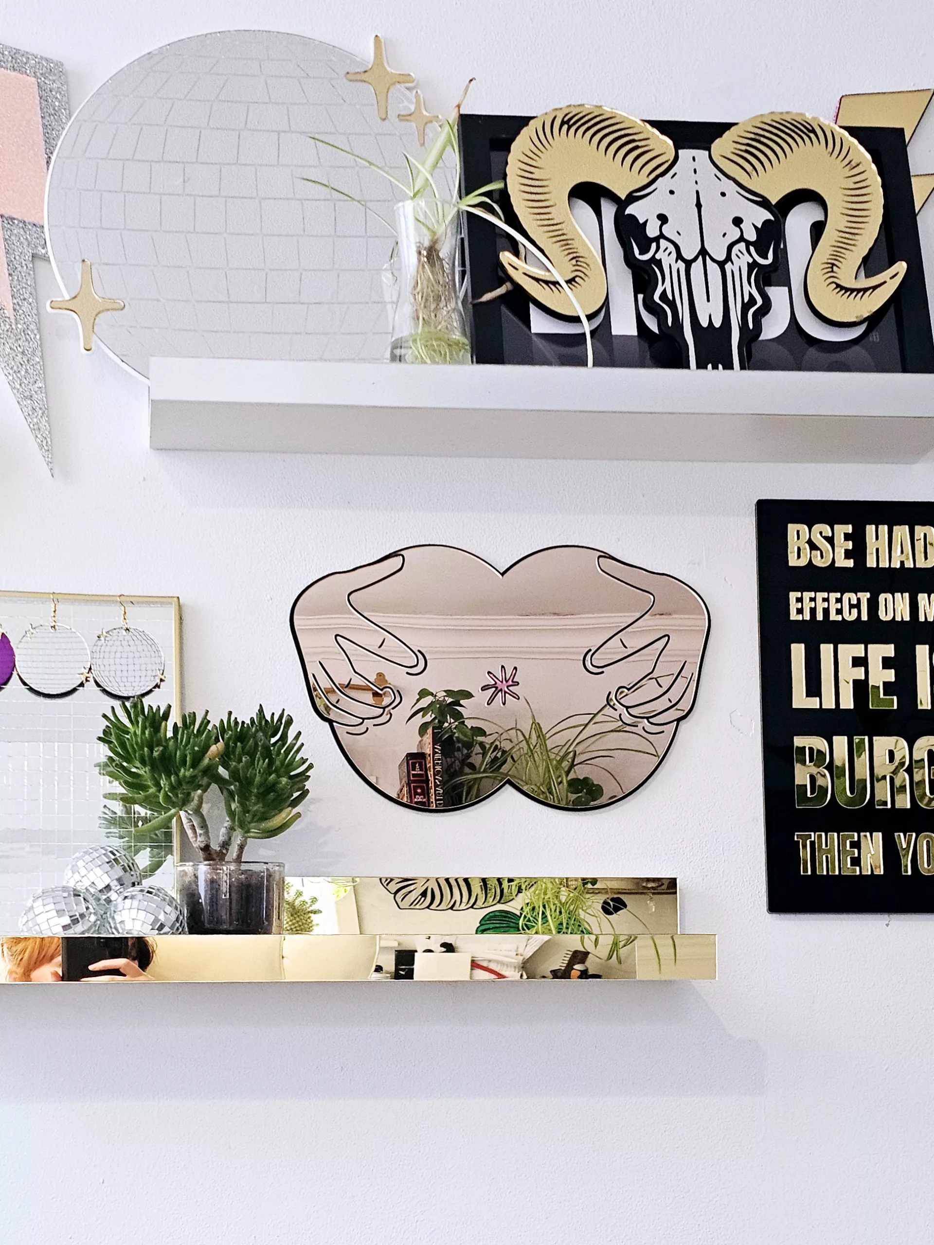 A handmade mirror in the shape of a butthole. The mirror hands pulling the butthole open.