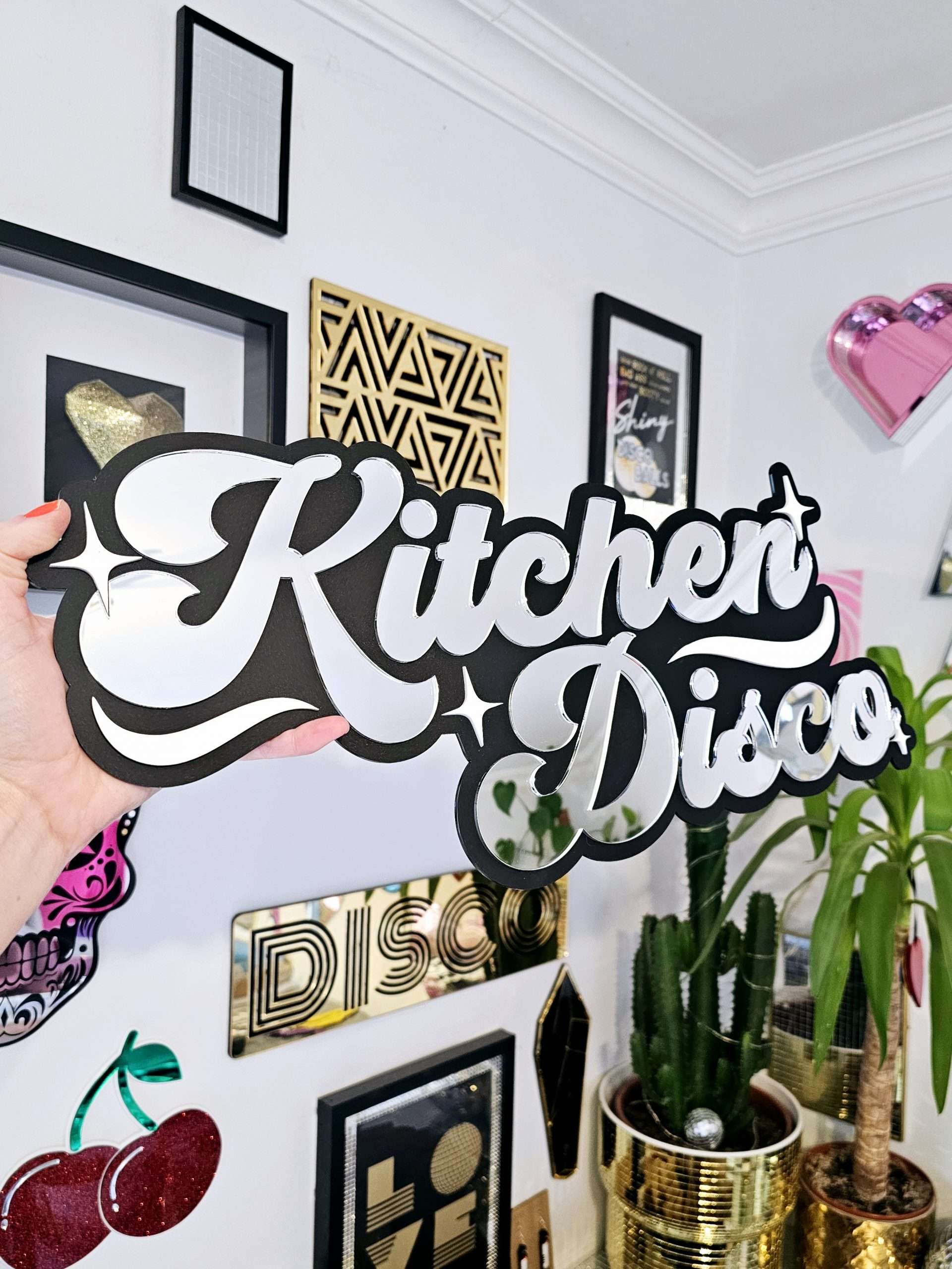 A sign that says Kitchen Disco. Made with a black backing and silver lettering.