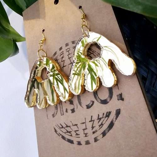 A pair of handmade earrings in the shape of the monster munch snack, made from gold mirrored acrylic.