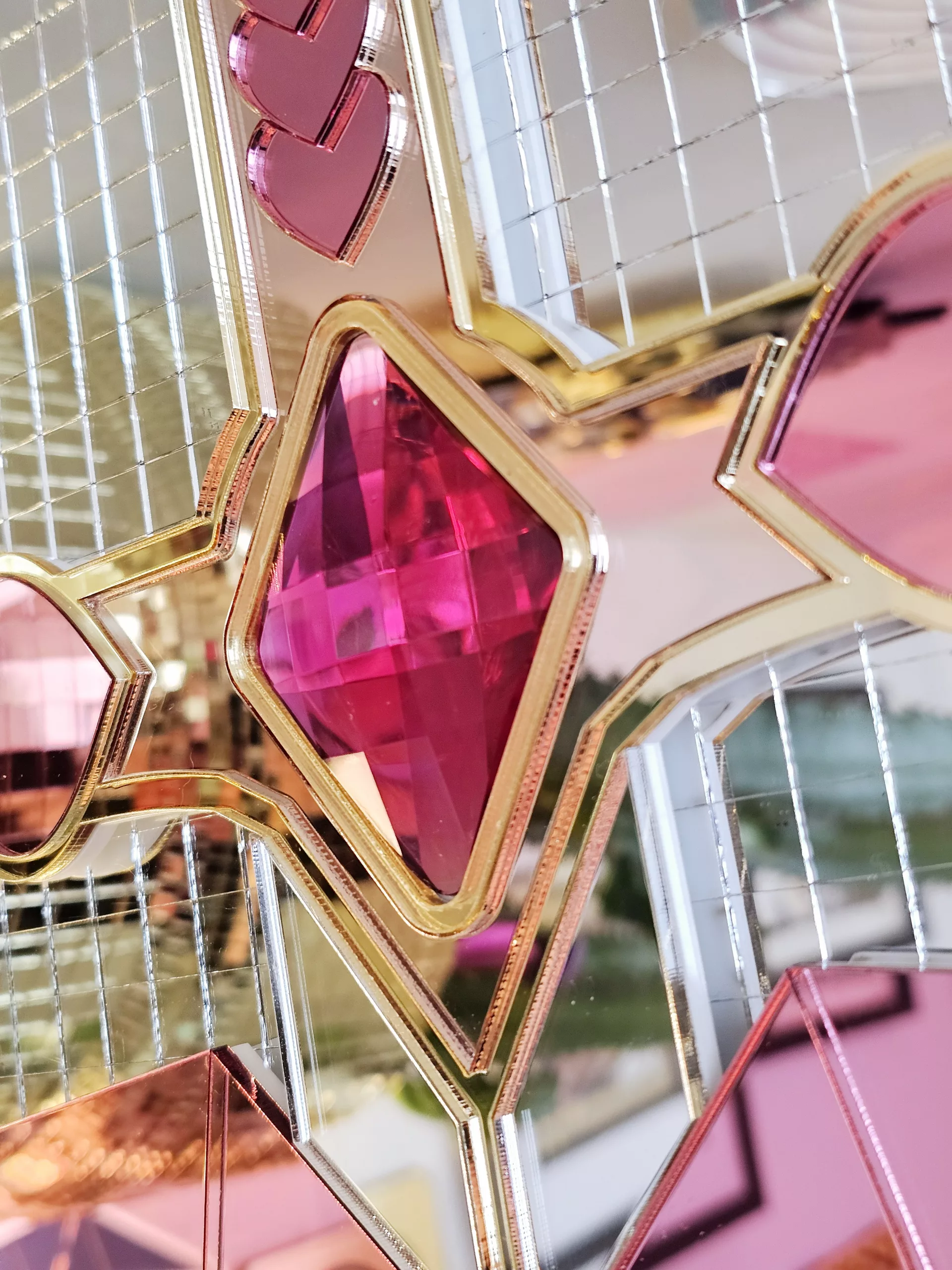 A handmade mirror on the shape of a sword piercing a heart. Made with gold, rose gold, pink and silver mirror with gem accents.