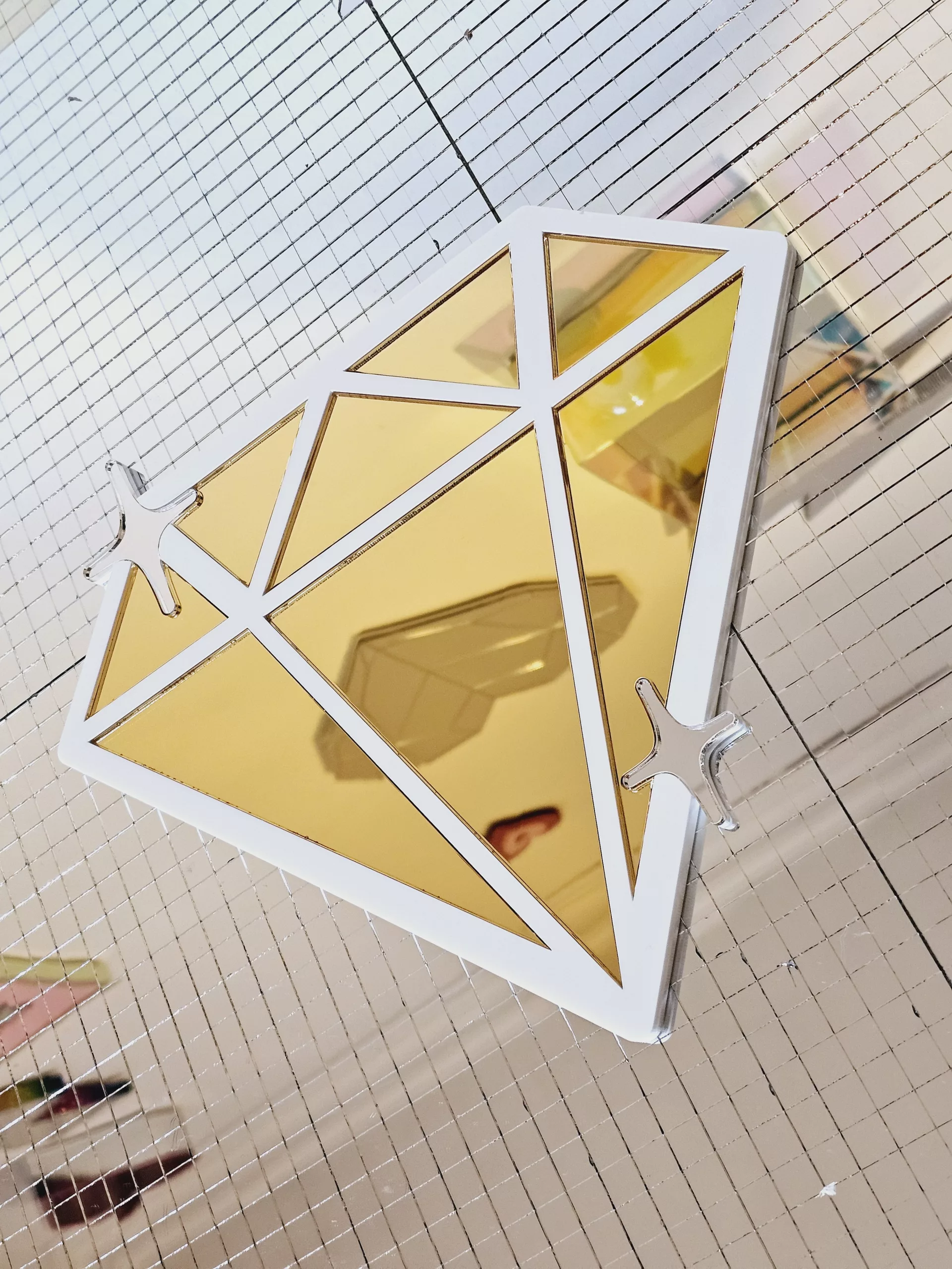 A handmade mirror in the shape of a diamond,