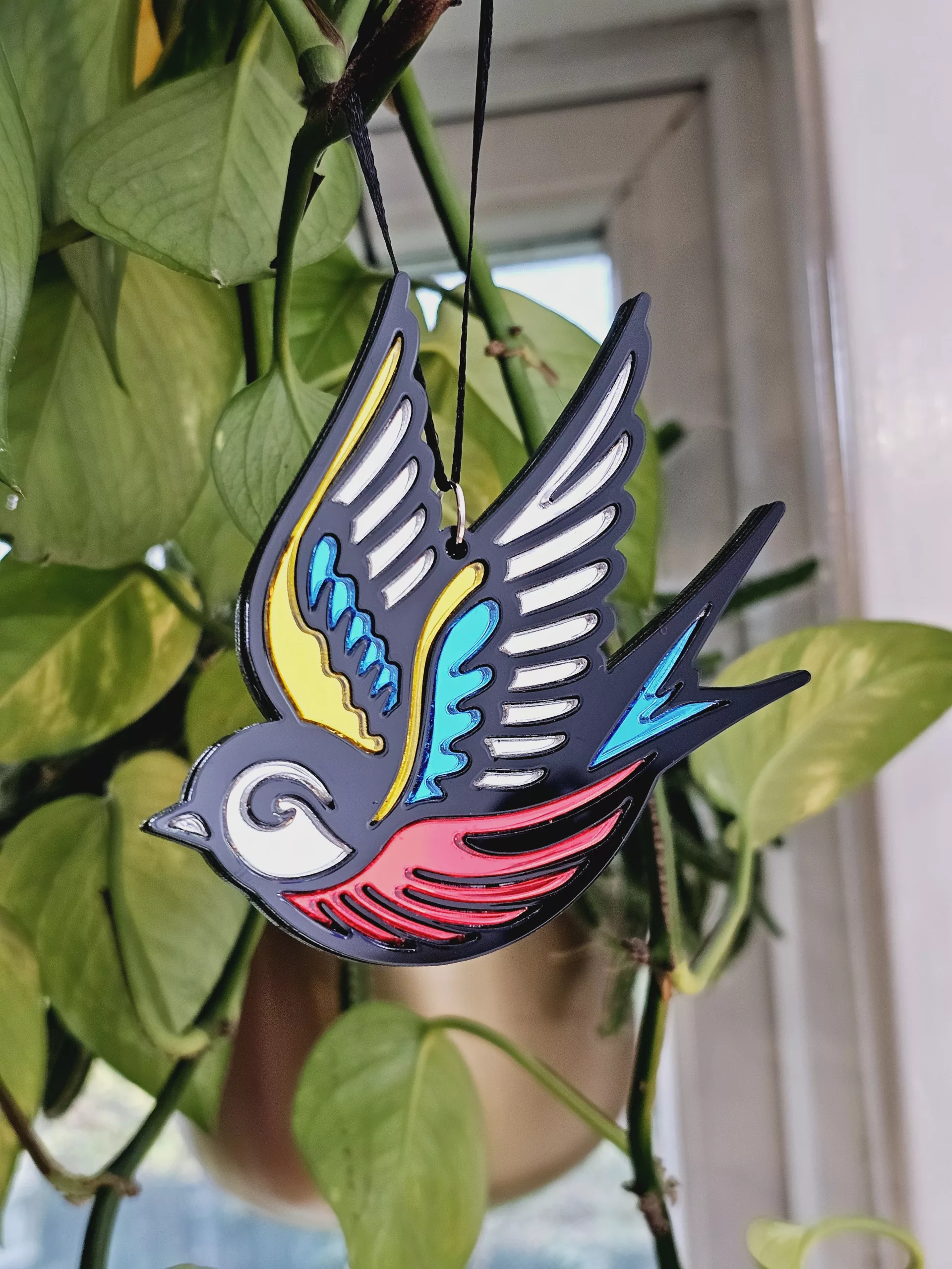 A Christmas tree ornament in the shape of a swallow. Made in a traditional tattoo style.