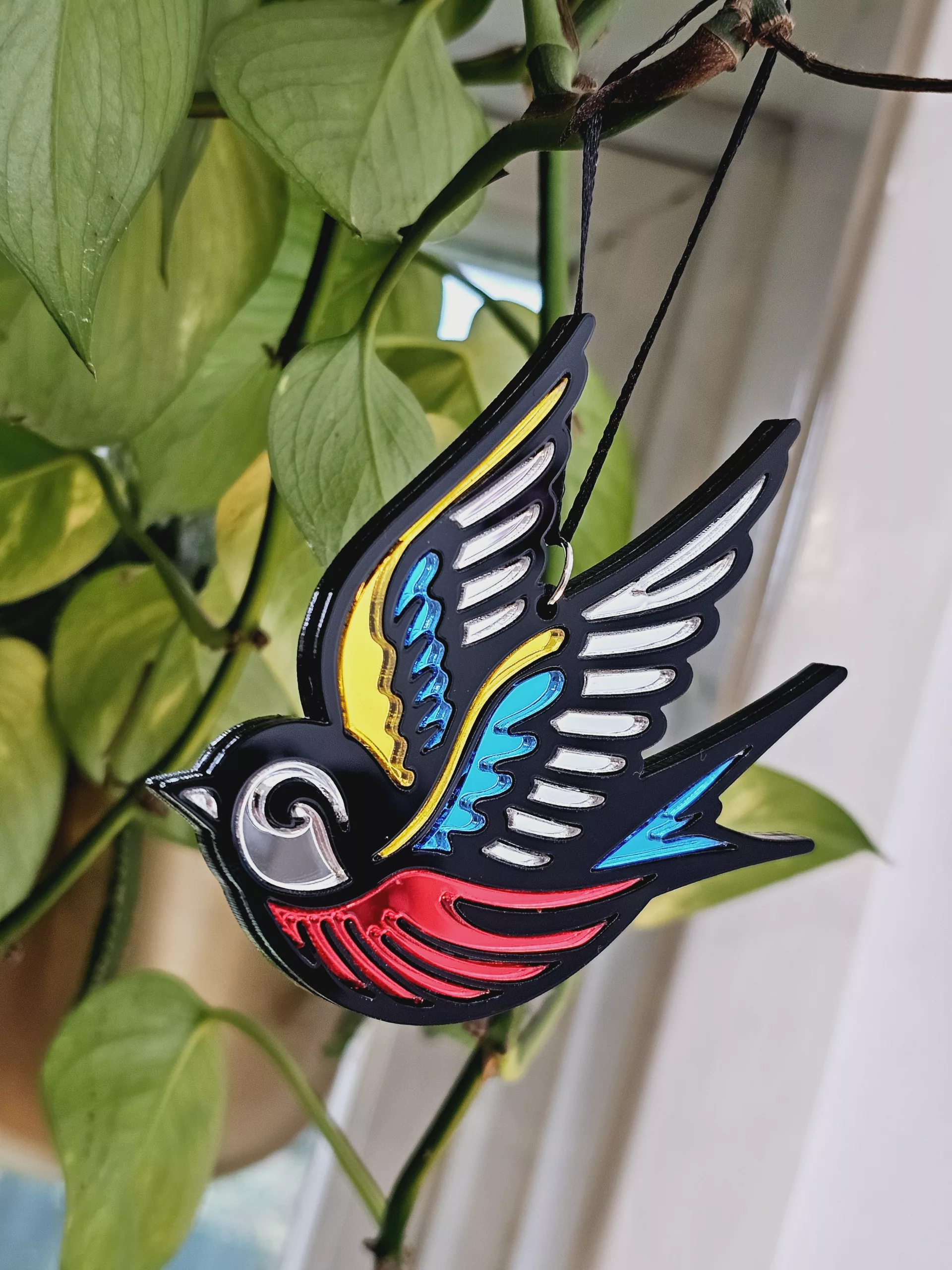 A Christmas tree ornament in the shape of a swallow. Made in a traditional tattoo style.