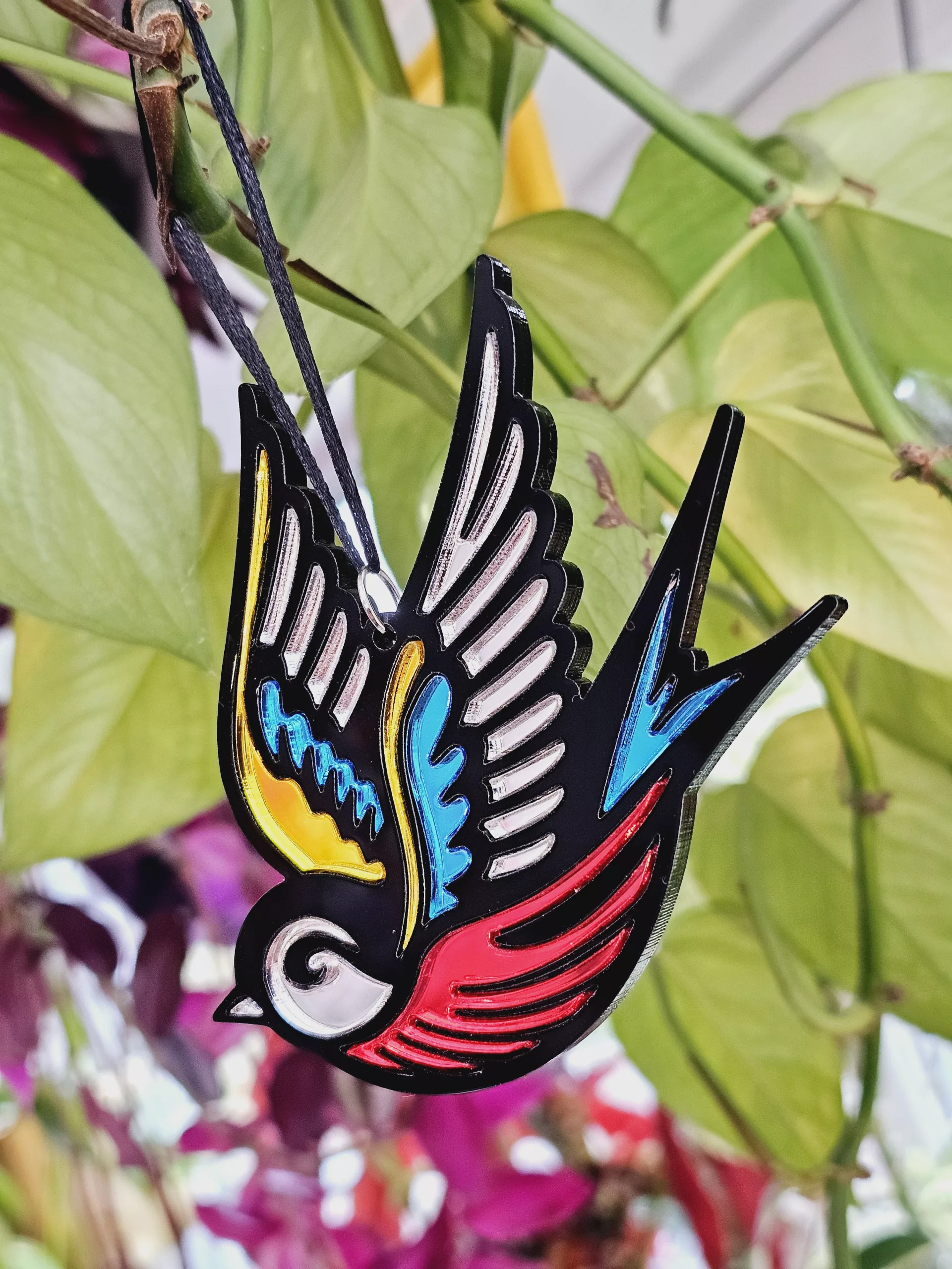 A Christmas tree ornament in the shape of a swallow. Made in a traditional tattoo style.
