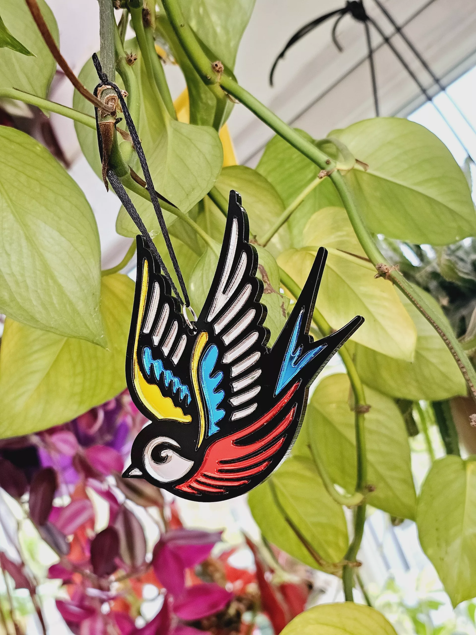 A Christmas tree ornament in the shape of a swallow. Made in a traditional tattoo style.