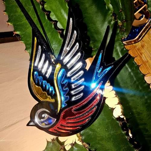 A Christmas tree ornament in the shape of a swallow. Made in a traditional tattoo style.