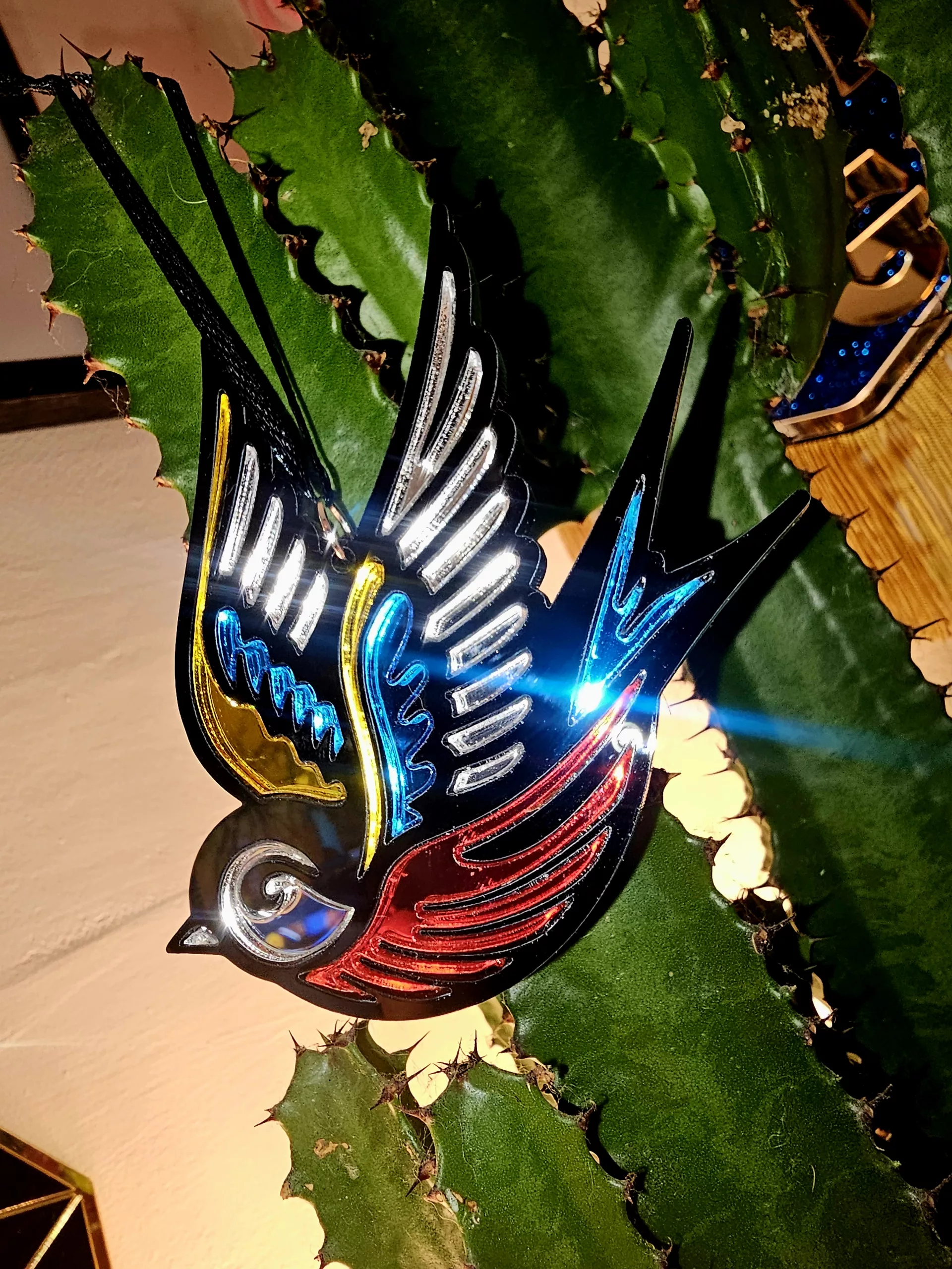 A Christmas tree ornament in the shape of a swallow. Made in a traditional tattoo style.