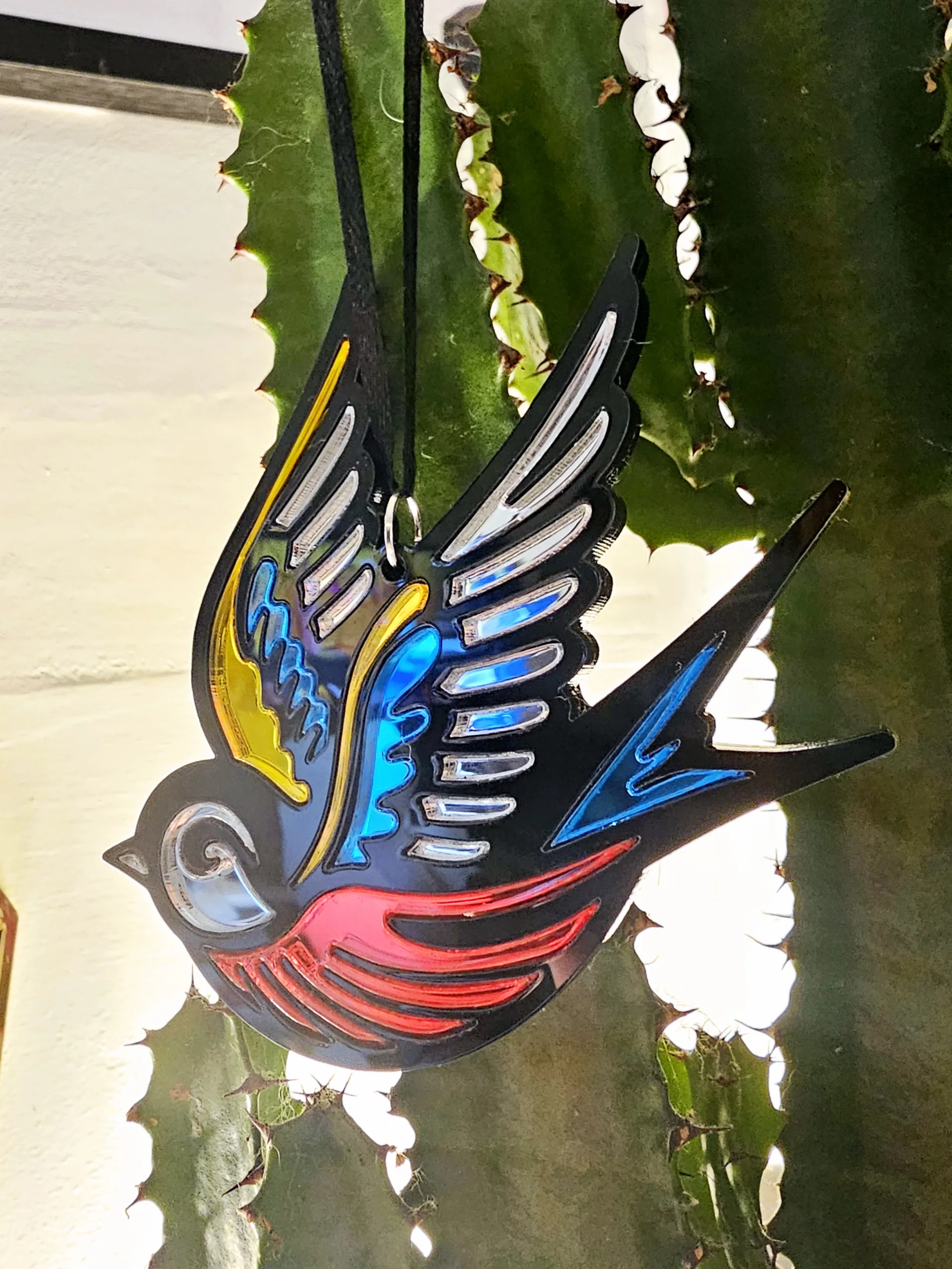 A Christmas tree ornament in the shape of a swallow. Made in a traditional tattoo style.